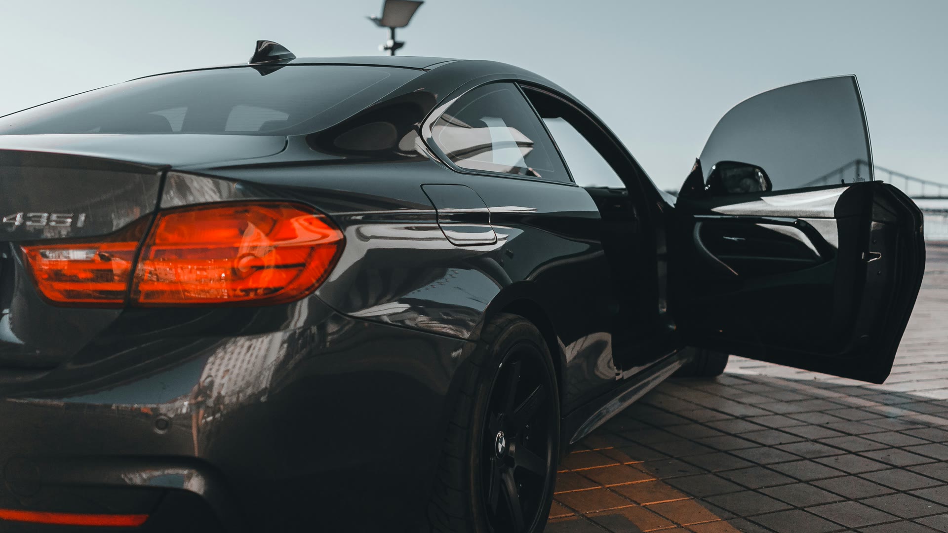 Car tinting Perth: black BMW with freshly tinted windows at dusk, driver's door open